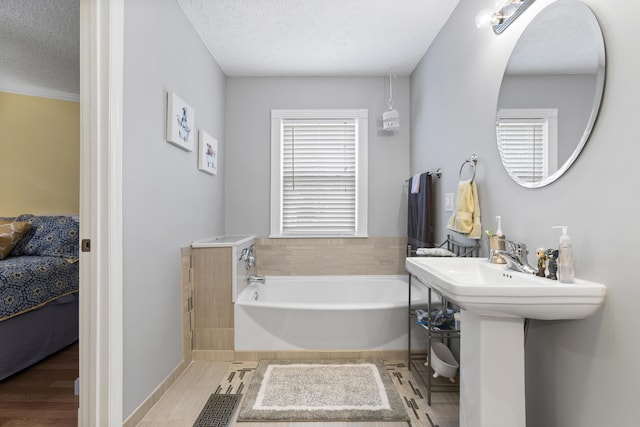 full bath with a textured ceiling, connected bathroom, and a bath