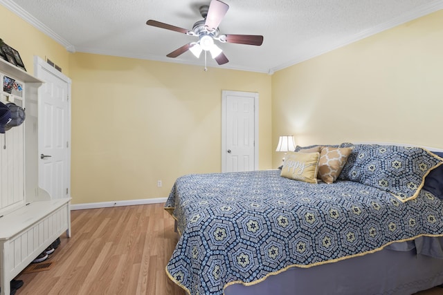 bedroom with light wood-style floors, a textured ceiling, baseboards, and crown molding