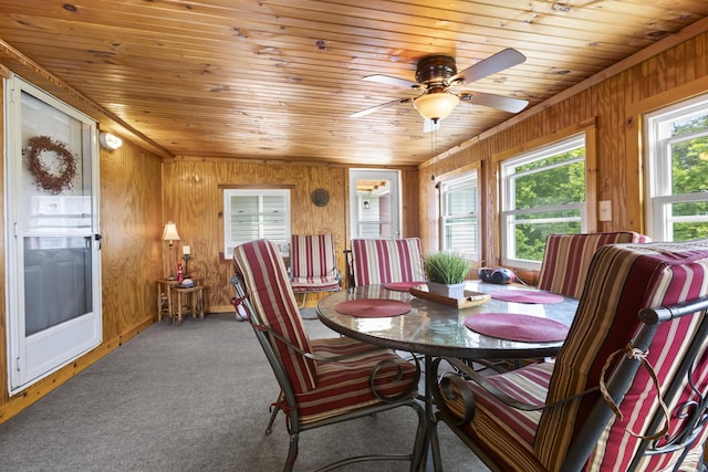 dining room with carpet floors, wooden ceiling, and wooden walls