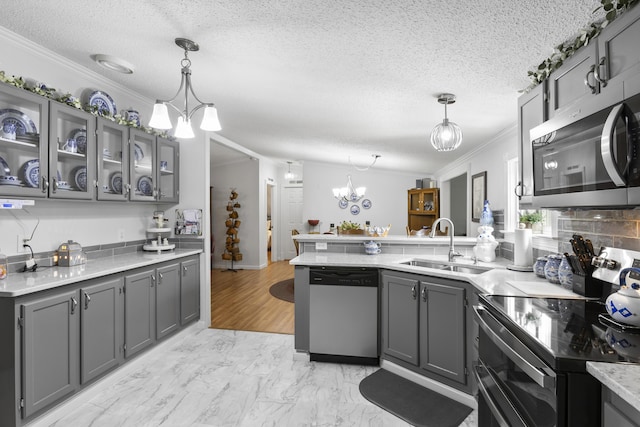 kitchen featuring appliances with stainless steel finishes, decorative light fixtures, gray cabinets, crown molding, and a sink