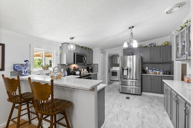 kitchen with a peninsula, appliances with stainless steel finishes, a kitchen breakfast bar, and decorative light fixtures