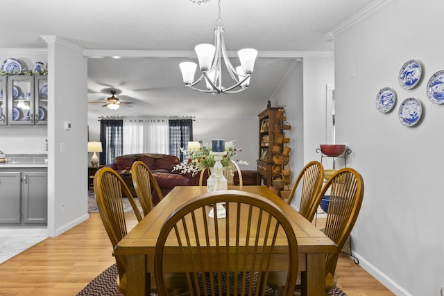 dining space with light wood-type flooring, crown molding, baseboards, and ceiling fan with notable chandelier