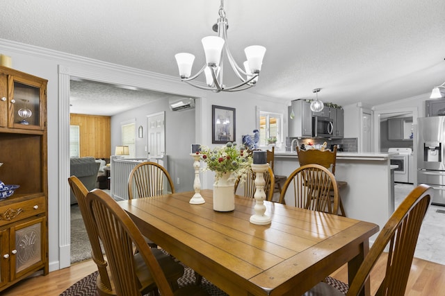 dining area with ornamental molding, an AC wall unit, a textured ceiling, and light wood finished floors