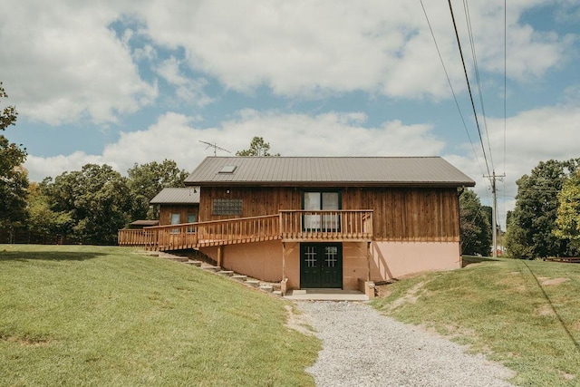 back of house with metal roof, a lawn, and a wooden deck