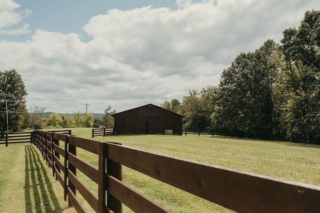 view of yard with an outbuilding, fence, an outdoor structure, and a rural view