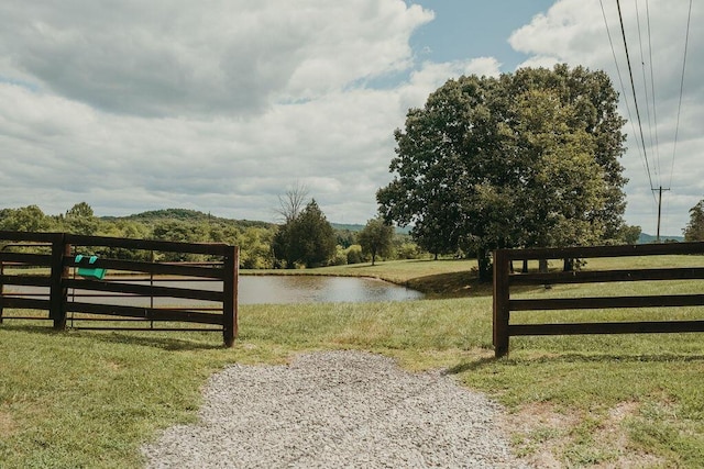 view of gate featuring a water view, fence, and a yard