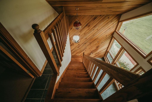 stairs featuring wood walls, wooden ceiling, and a towering ceiling