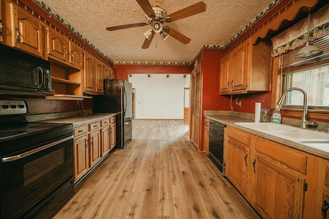 kitchen with light wood-style flooring, brown cabinets, light countertops, black appliances, and a sink