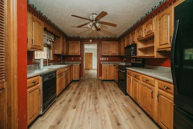 kitchen featuring light wood-style floors, brown cabinets, a sink, and black appliances