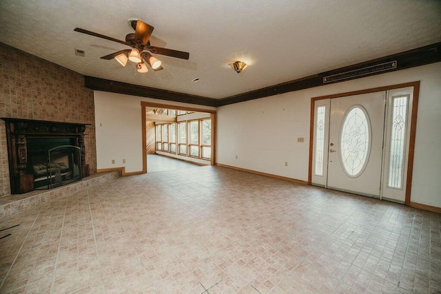 unfurnished living room featuring a textured ceiling, a fireplace, visible vents, and baseboards