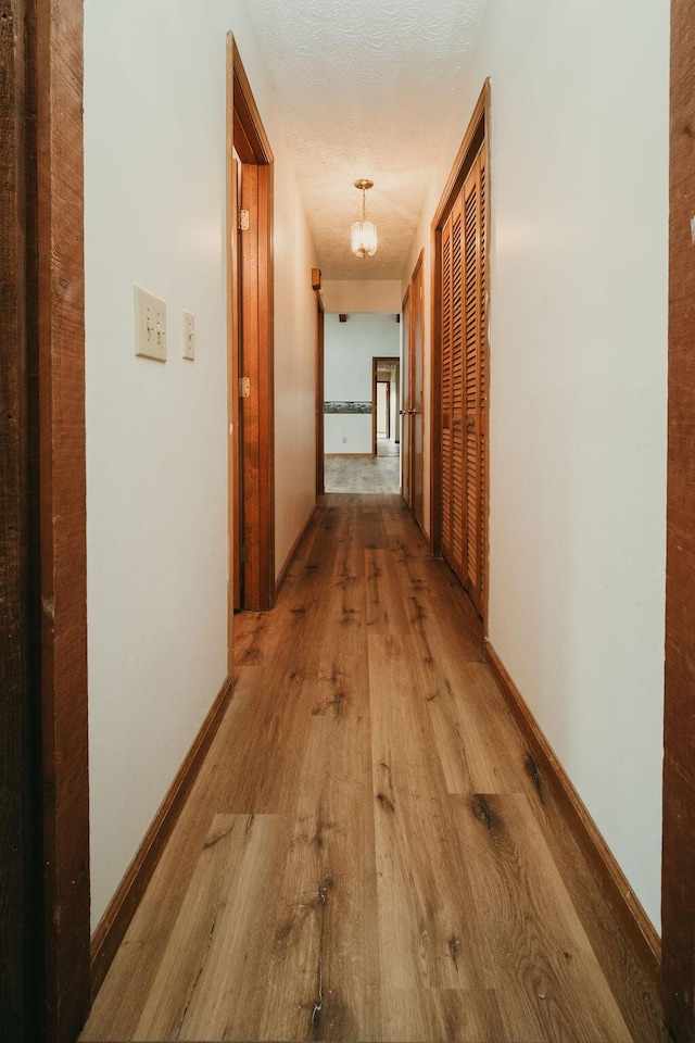 hall featuring light wood-type flooring and baseboards