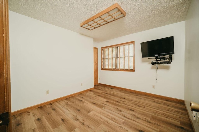 unfurnished room featuring a textured ceiling, baseboards, and wood finished floors