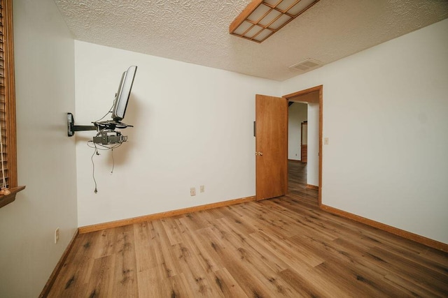 unfurnished room featuring a textured ceiling, baseboards, and light wood-style floors