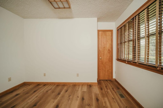 empty room featuring baseboards, visible vents, and wood finished floors