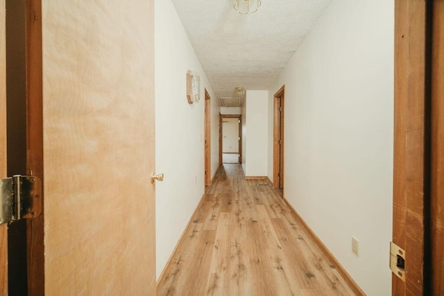 hallway featuring a textured ceiling and light wood-type flooring