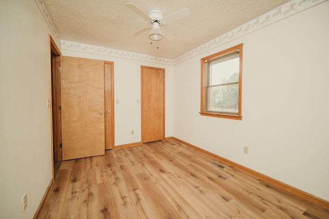 unfurnished bedroom featuring visible vents, light wood-style floors, ceiling fan, a textured ceiling, and baseboards