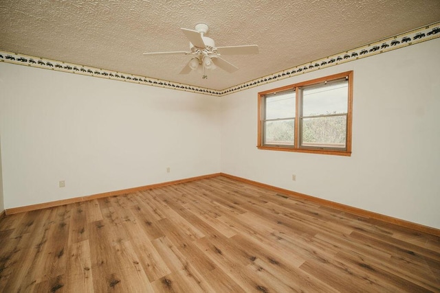 spare room with a textured ceiling, baseboards, and wood finished floors