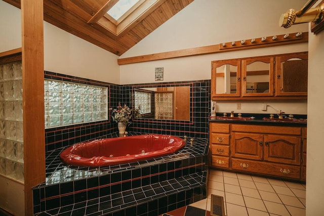 full bath featuring visible vents, lofted ceiling with skylight, tile patterned floors, a jetted tub, and vanity