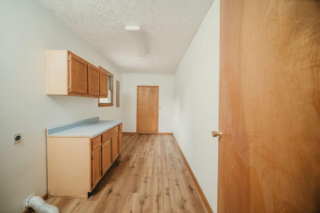 interior space featuring baseboards, a textured ceiling, and light wood finished floors