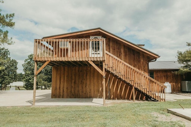 back of property with a deck, a lawn, central AC unit, and stairs