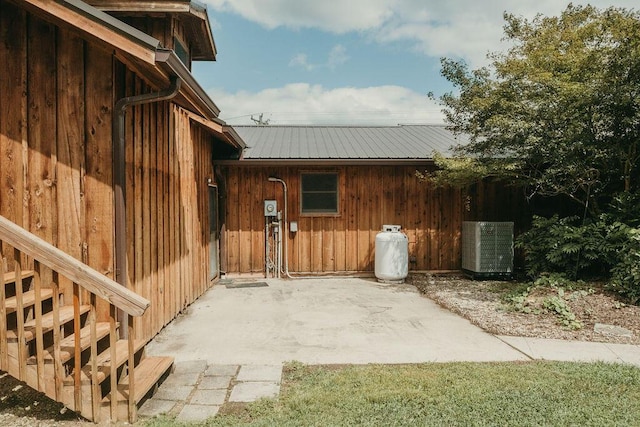 view of side of property featuring a patio area, central AC unit, metal roof, and board and batten siding