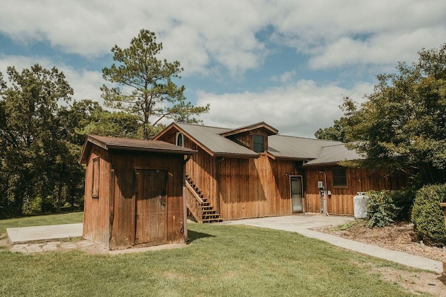 exterior space featuring metal roof, stairway, and a front lawn