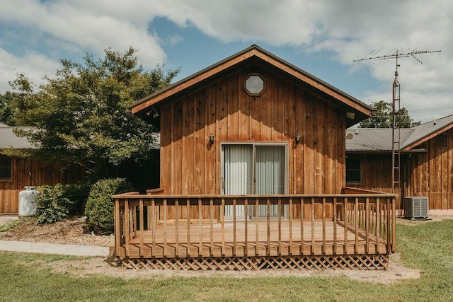 rear view of property with a deck, metal roof, central AC, and a yard