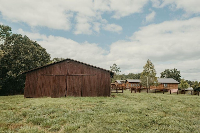 view of outdoor structure featuring an outbuilding, a rural view, and fence