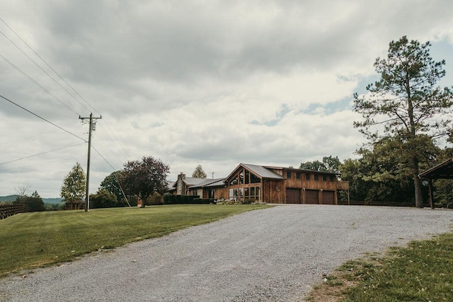 view of front facade with a garage, gravel driveway, and a front lawn