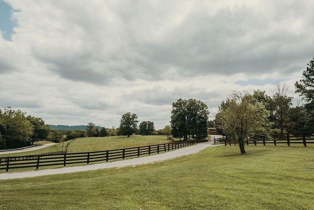 surrounding community featuring fence, a lawn, and a rural view