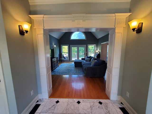 hallway with vaulted ceiling, marble finish floor, and baseboards