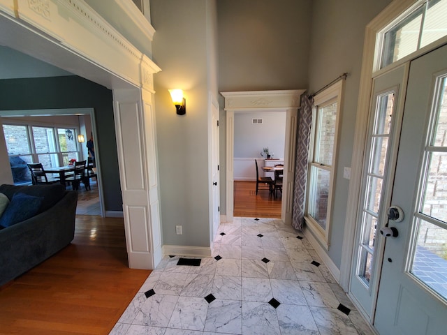 entryway with marble finish floor, a high ceiling, visible vents, and baseboards