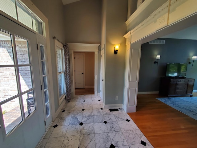 entrance foyer featuring a towering ceiling, marble finish floor, baseboards, and visible vents