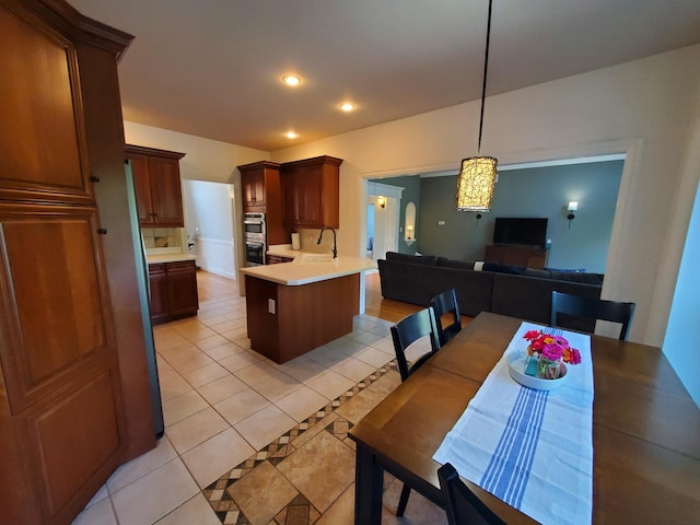 kitchen with open floor plan, decorative light fixtures, light countertops, a sink, and light tile patterned flooring