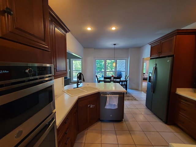 kitchen with appliances with stainless steel finishes, light countertops, a sink, and hanging light fixtures