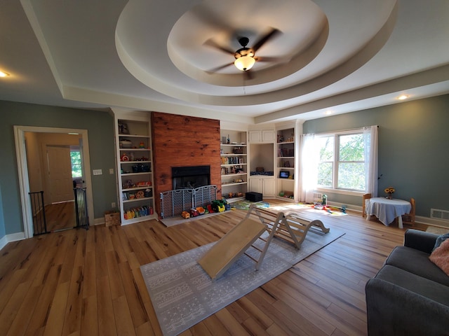 living room featuring baseboards, a raised ceiling, and hardwood / wood-style floors