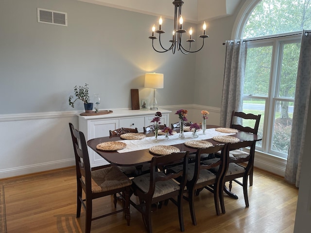 dining space with light wood-style floors, a wealth of natural light, a chandelier, and visible vents