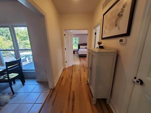 corridor with light wood-type flooring and baseboards