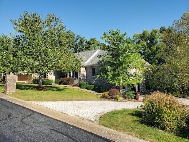 view of property hidden behind natural elements featuring driveway and a front lawn