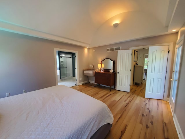 bedroom featuring visible vents, baseboards, light wood-style flooring, vaulted ceiling, and a sink