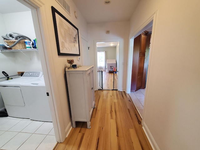 hallway with visible vents, baseboards, washer and dryer, and light wood-style floors