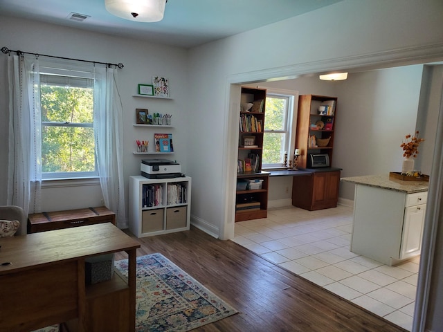 office space featuring visible vents, baseboards, a wealth of natural light, and light wood-style floors