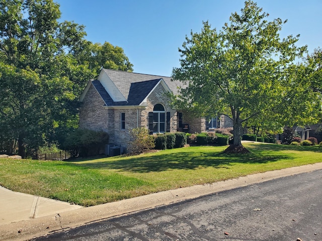 view of front of home with stone siding, a front lawn, and cooling unit