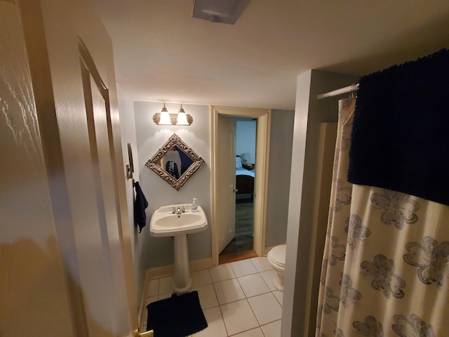 bathroom with tile patterned flooring, toilet, a sink, baseboards, and a shower with curtain