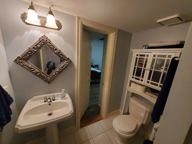 half bath with a sink, tile patterned flooring, toilet, and baseboards