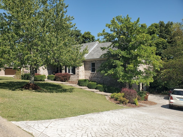 view of property hidden behind natural elements featuring brick siding and a front lawn