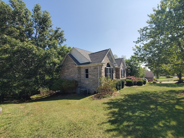 view of home's exterior with central air condition unit, a lawn, and brick siding