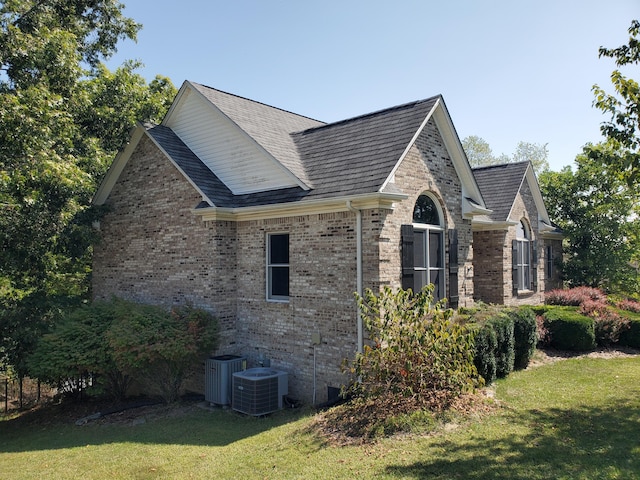 view of home's exterior featuring central AC unit, a lawn, and brick siding