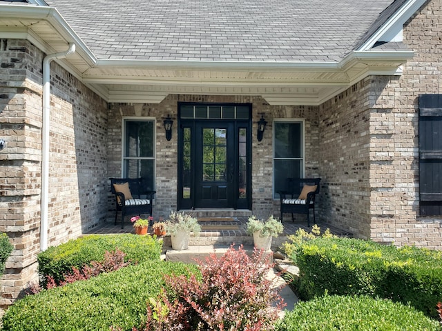 view of exterior entry featuring covered porch and brick siding