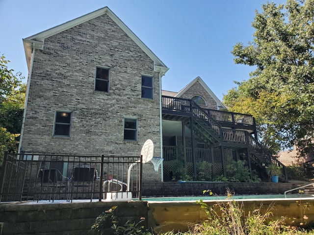 back of property with a wooden deck, stairs, and brick siding